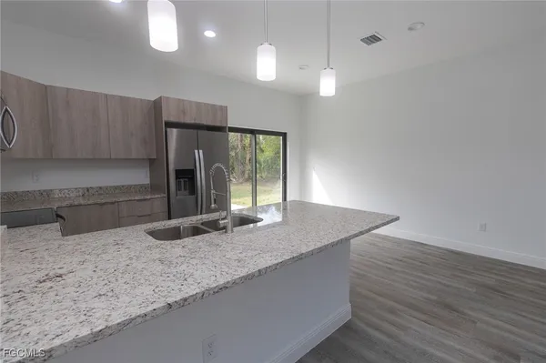 a kitchen with granite countertop a sink a counter space and cabinets