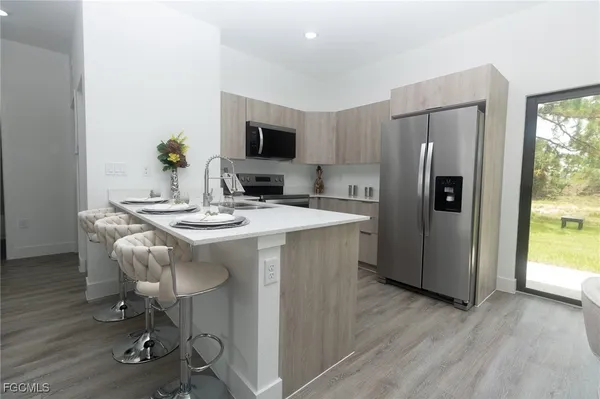 a kitchen with stainless steel appliances kitchen island granite countertop a refrigerator a stove a microwave cabinets and wooden floor