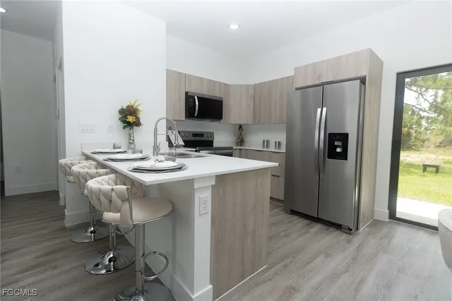 a kitchen with stainless steel appliances kitchen island granite countertop a refrigerator a stove a microwave cabinets and wooden floor