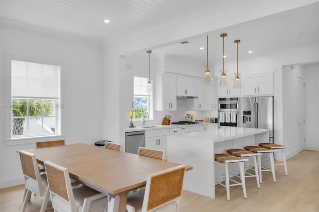 a kitchen with stainless steel appliances a sink a stove a refrigerator cabinets and wooden floor