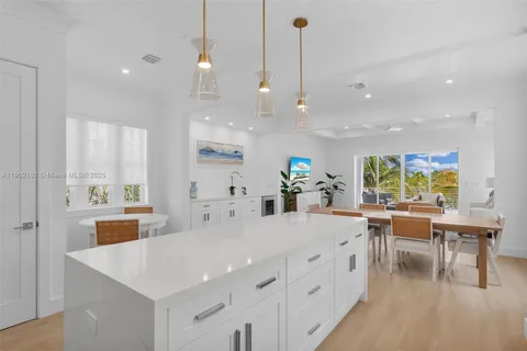 a large kitchen with kitchen island a large island a sink a stove and a chandelier