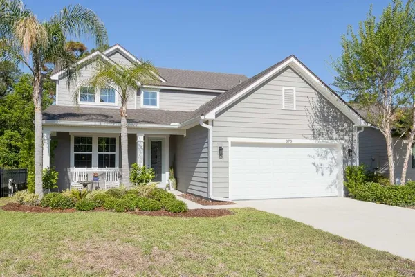 a front view of a house with a yard and potted plants