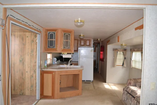 a kitchen with stainless steel appliances granite countertop a refrigerator a stove and a sink with large windows