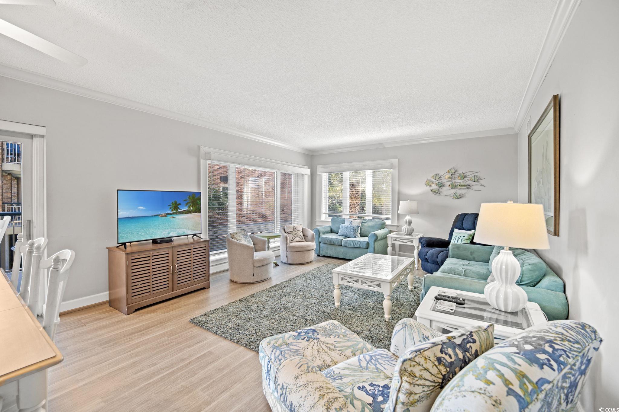 320 Myrtle Avenue Pawleys Island, SC 29585 - Photo 14 of 38 Living area featuring ornamental molding, light wood-style flooring, and a textured ceiling