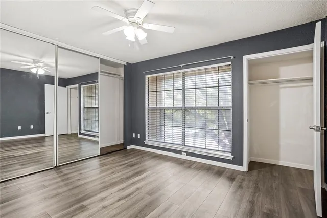 an empty room with wooden floor and a ceiling fan