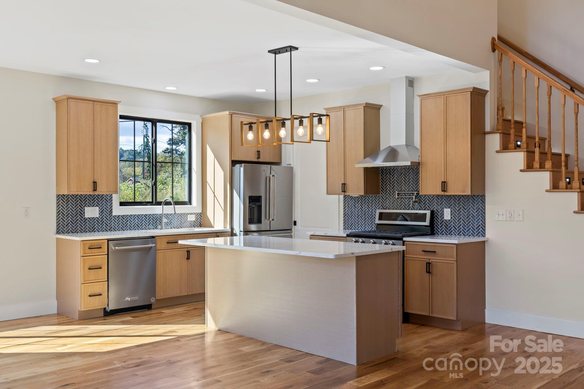 154 Osceola Road Hendersonville, NC 28739 - Photo 18 of 38 a kitchen with stainless steel appliances granite countertop a sink a stove a refrigerator and island with wooden floor