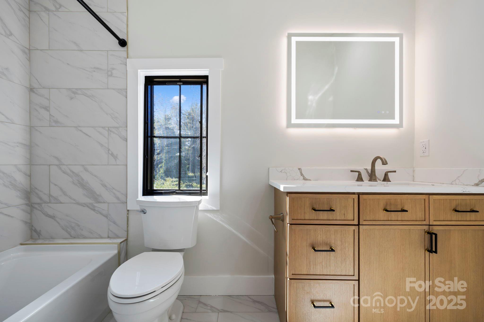 154 Osceola Road Hendersonville, NC 28739 - Photo 32 of 38 a bathroom with a toilet sink vanity tub and mirror