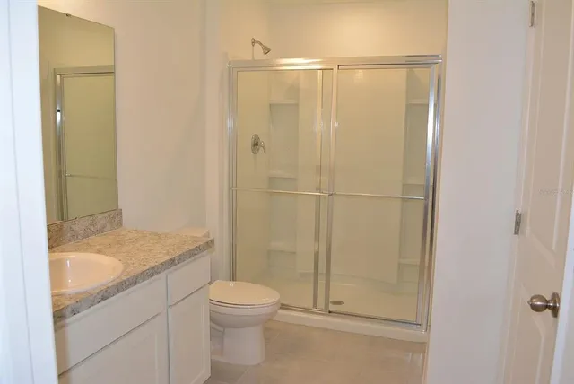 a bathroom with a granite countertop sink a toilet and shower