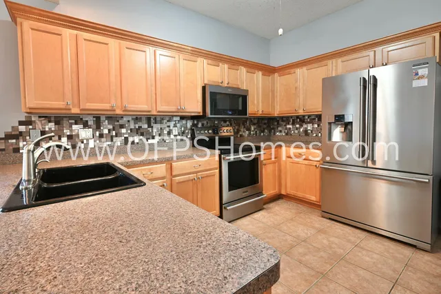 a kitchen with stainless steel appliances granite countertop a refrigerator stove top oven and sink