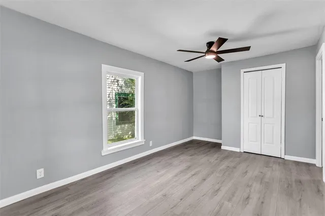 a view of an empty room with a window and wooden floor