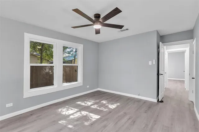 a view of an empty room with a window and wooden floor