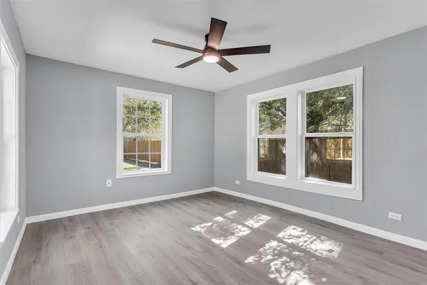 a view of an empty room with a window and wooden floor