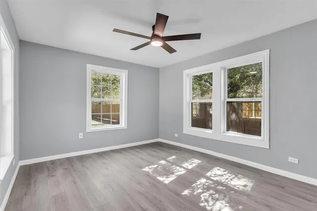a view of an empty room with a window and wooden floor
