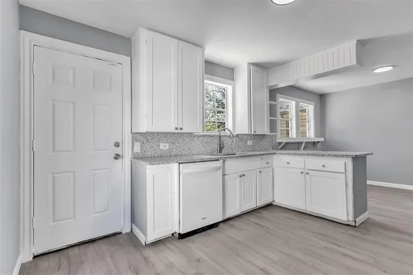 a white kitchen with granite countertop cabinets and a sink
