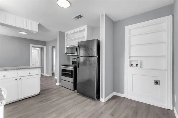 a kitchen with granite countertop stainless steel appliances a refrigerator and cabinets