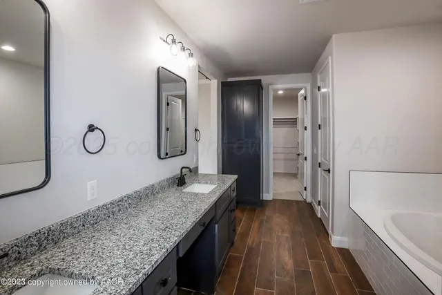 a bathroom with a granite countertop sink mirror and a bathtub