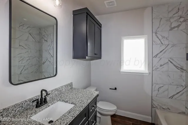 a bathroom with a granite countertop sink toilet and mirror