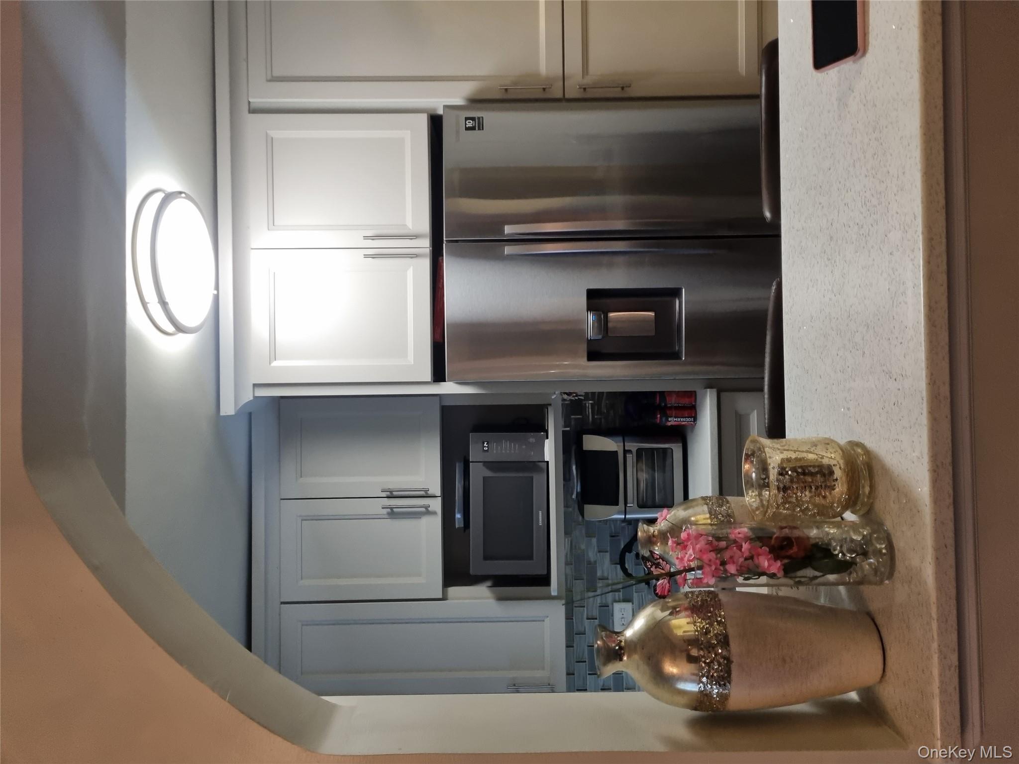 141-34 78th Avenue, Unit 1C Queens, NY 11367 - Photo 12 of 16 Kitchen with stainless steel fridge, light stone countertops, tasteful backsplash, and white cabinets