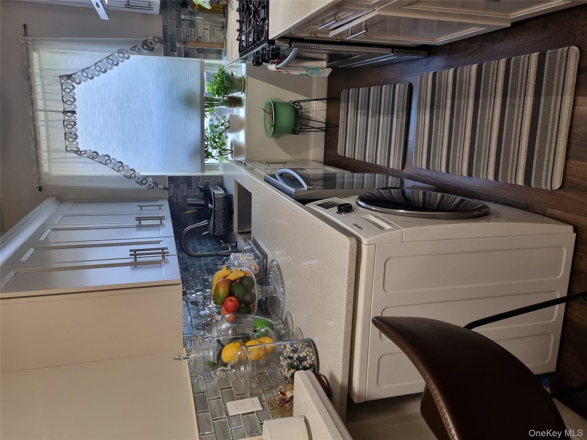 141-34 78th Avenue, Unit 1C Queens, NY 11367 - Photo 14 of 16 Kitchen featuring backsplash, range, washer / dryer, dark wood-type flooring, and light stone countertops
