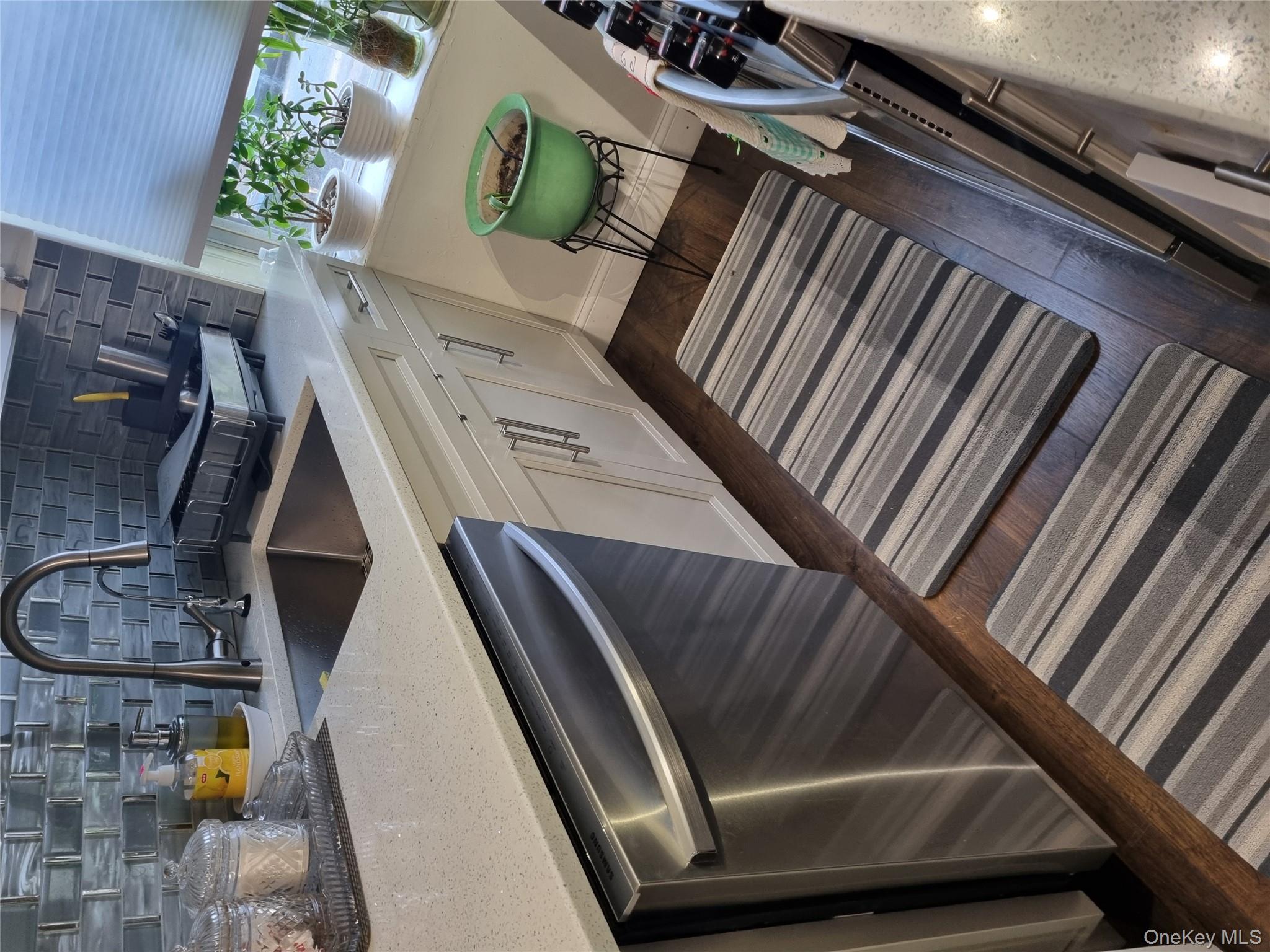 141-34 78th Avenue, Unit 1C Queens, NY 11367 - Photo 16 of 16 Kitchen with stainless steel dishwasher, tasteful backsplash, light stone counters, white cabinets, and dark wood-type flooring