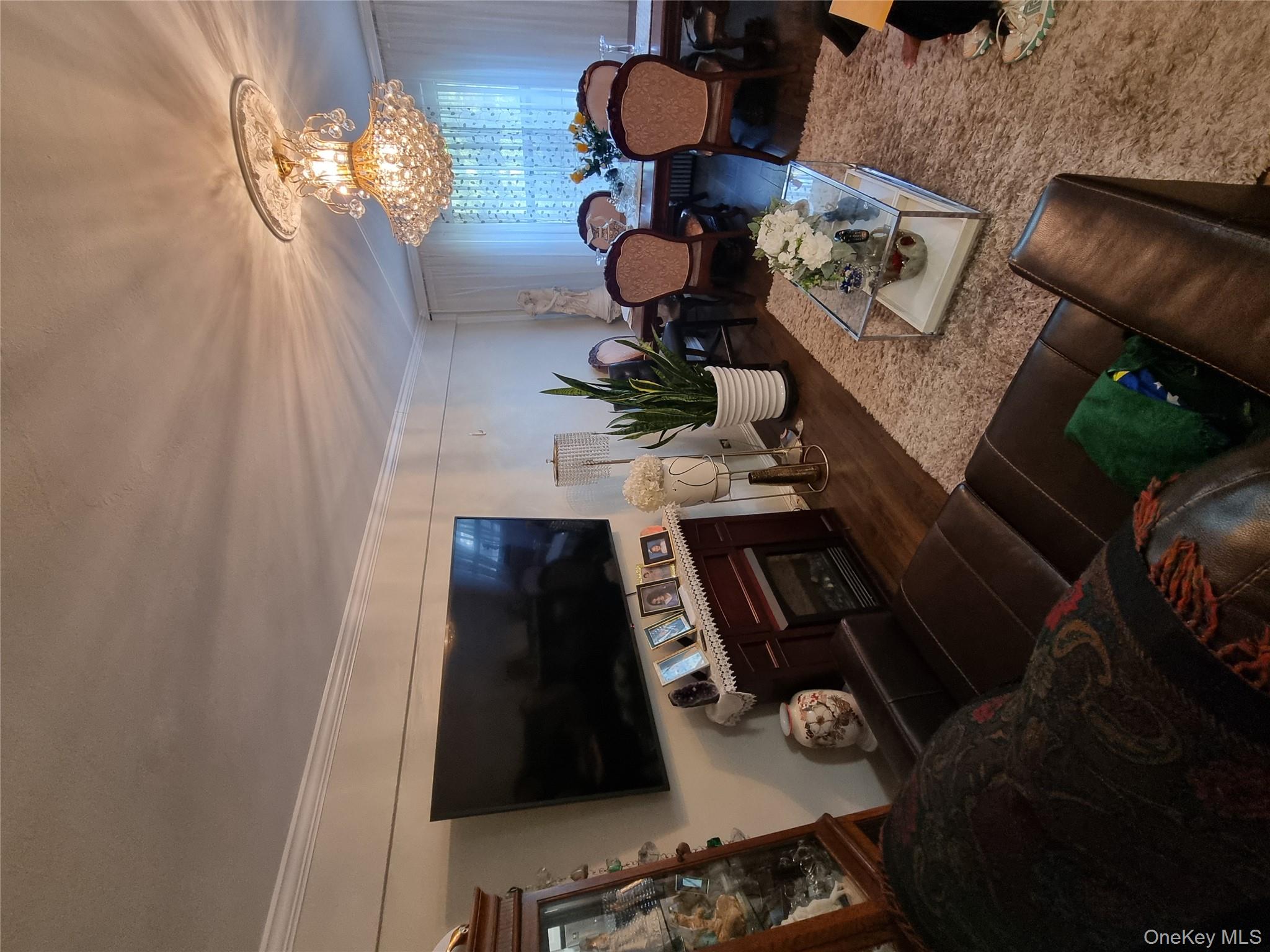 141-34 78th Avenue, Unit 1C Queens, NY 11367 - Photo 4 of 16 Living room with dark wood finished floors, ornamental molding, a chandelier, and a fireplace