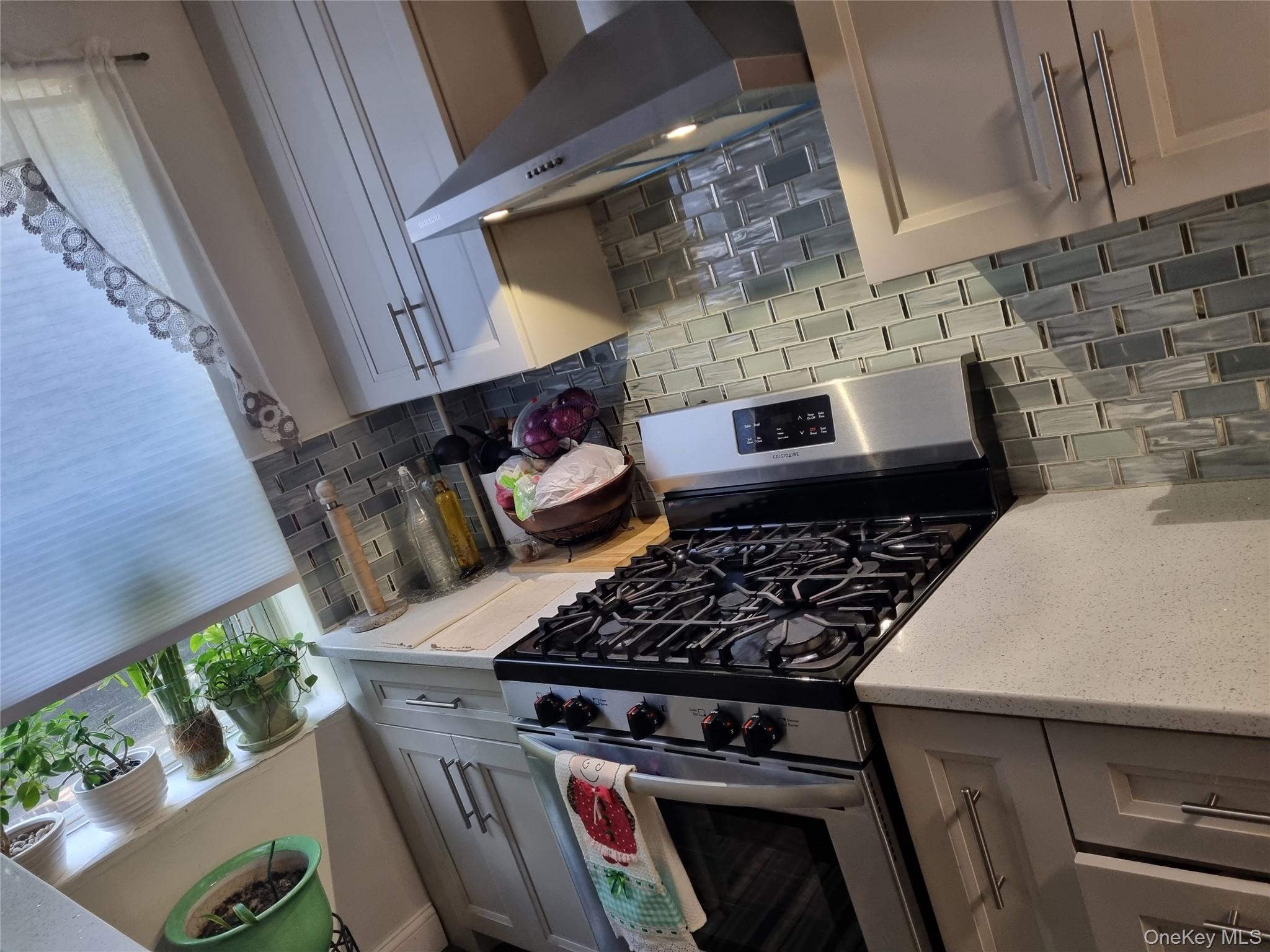 141-34 78th Avenue, Unit 1C Queens, NY 11367 - Photo 6 of 16 Kitchen featuring stainless steel gas range oven, decorative backsplash, under cabinet range hood, and light stone counters