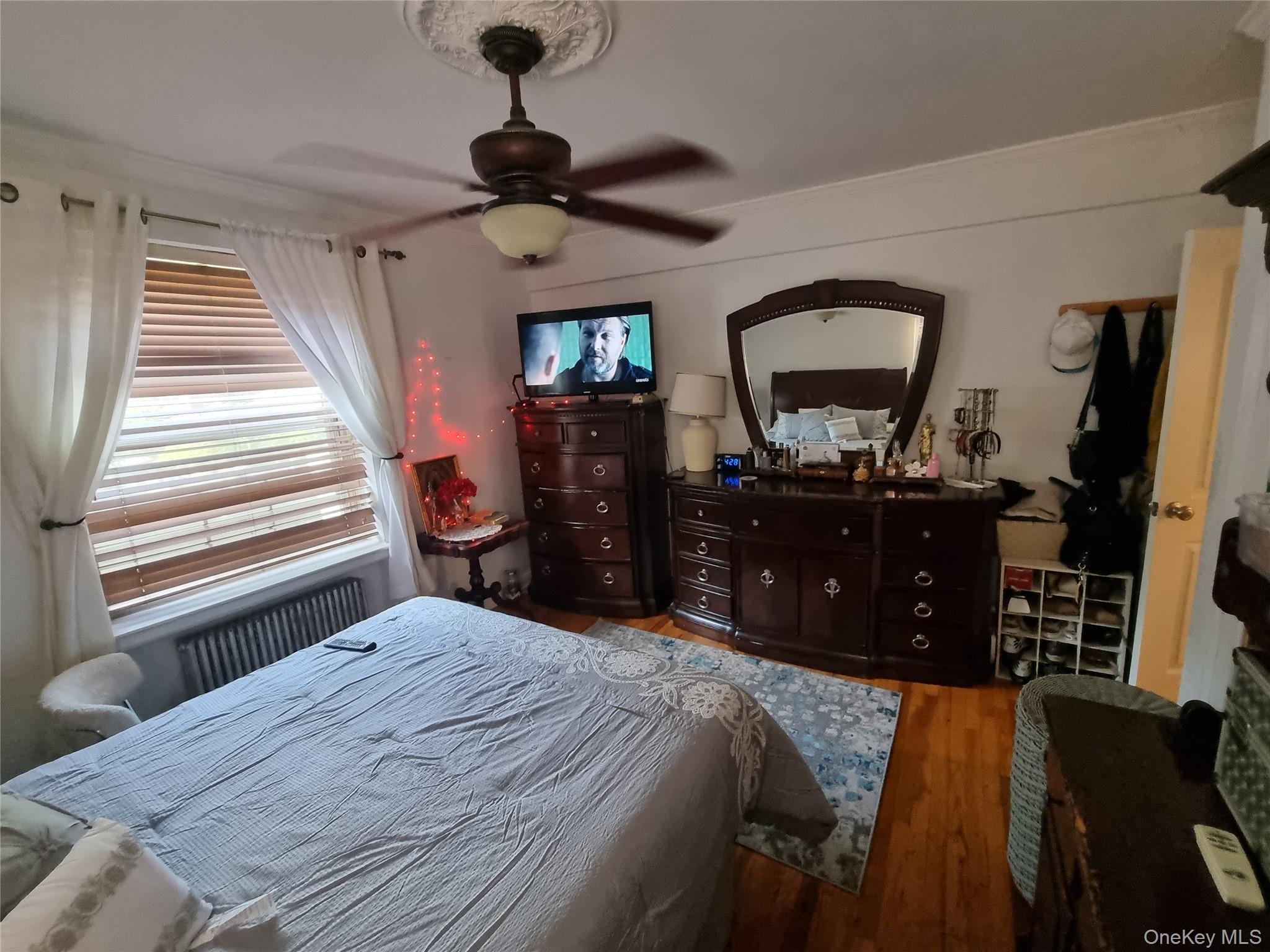141-34 78th Avenue, Unit 1C Queens, NY 11367 - Photo 7 of 16 Bedroom featuring radiator heating unit, wood finished floors, and ceiling fan