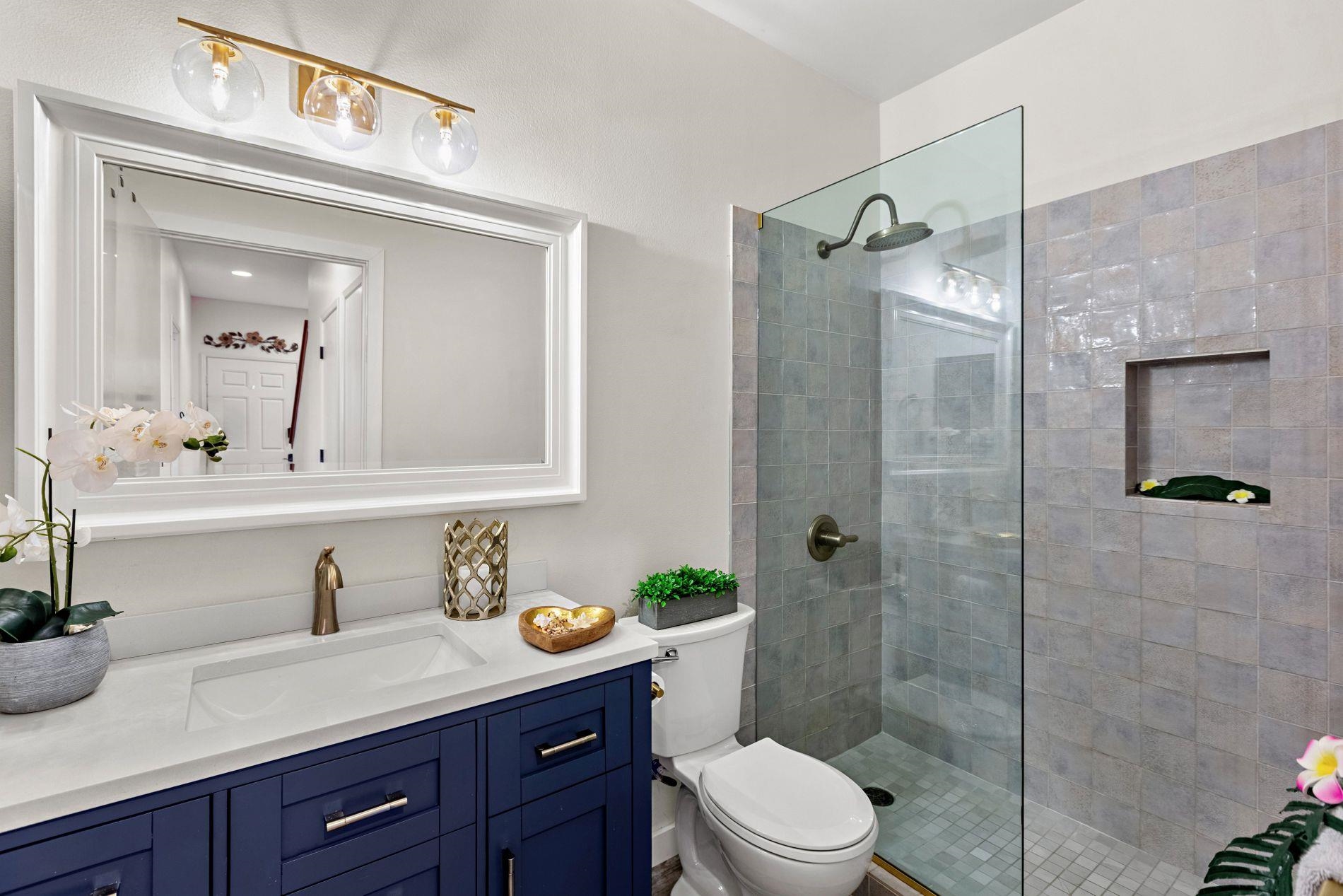 127 Punohu Lane, Unit 72 Lahaina, HI 96761 - Photo 21 of 43 a bathroom with a granite countertop sink toilet a mirror a shower and vanity