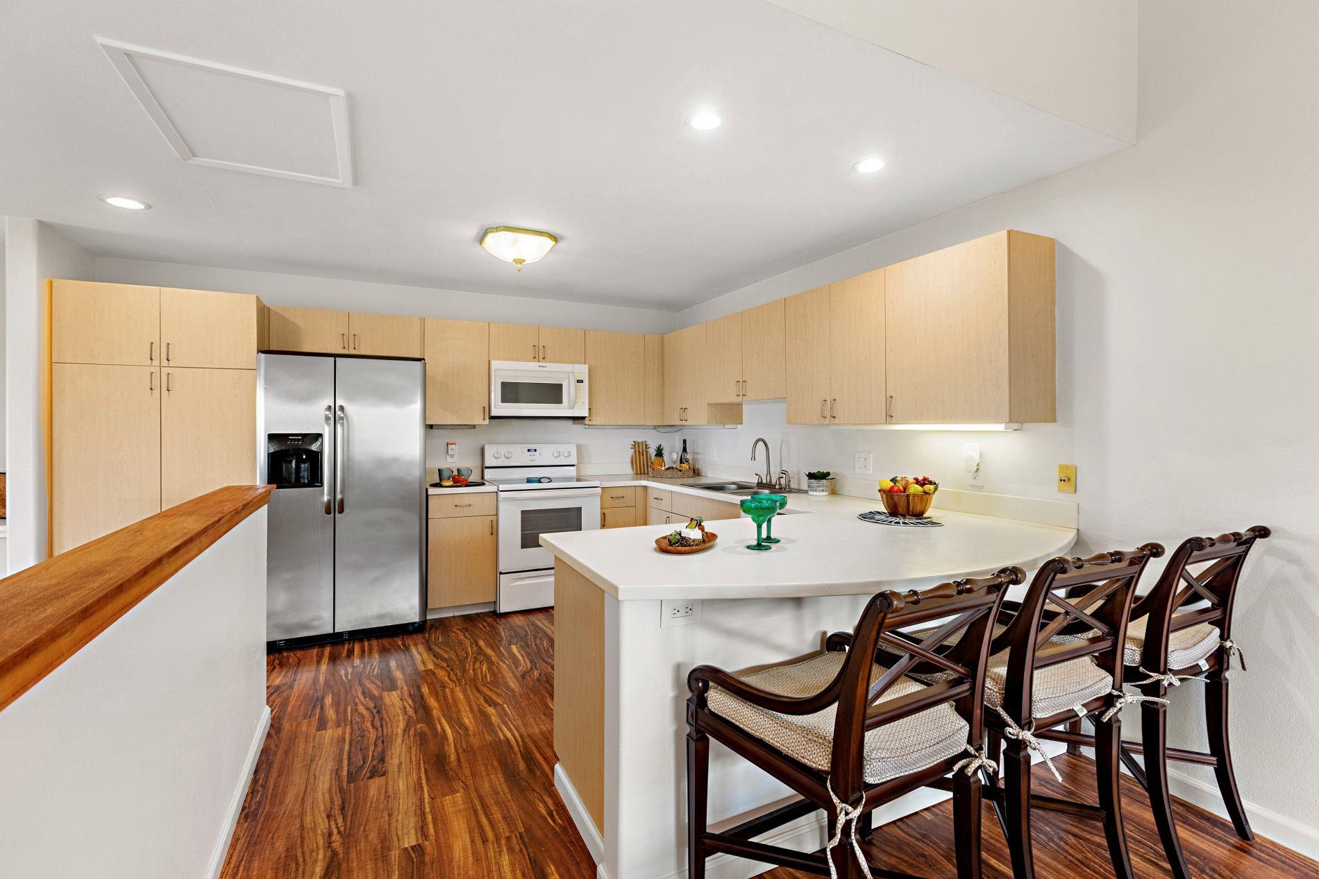 127 Punohu Lane, Unit 72 Lahaina, HI 96761 - Photo 6 of 43 a kitchen with stainless steel appliances a microwave a stove a sink dishwasher a stove a refrigerator with a dining table and chairs with wooden floor
