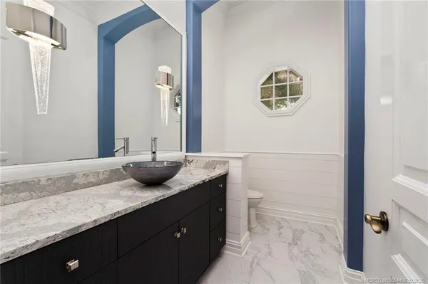 a bathroom with a granite countertop sink a mirror and a toilet