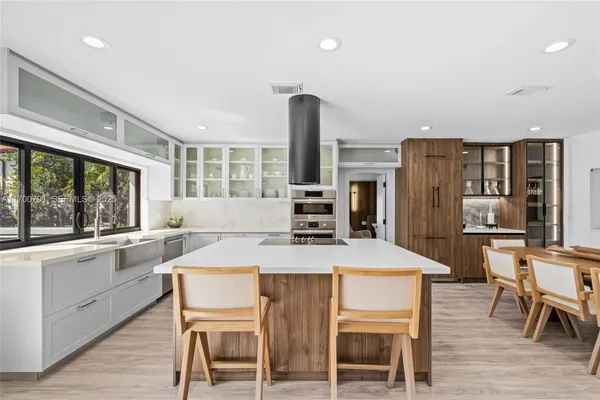a kitchen with stainless steel appliances a stove top oven a sink a dining table and chairs