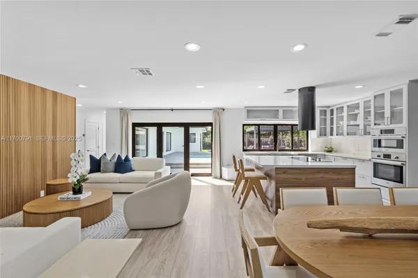 a living room with furniture a flat screen tv and kitchen view