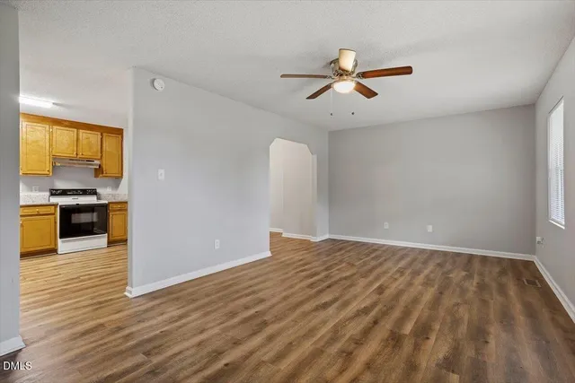 an empty room with wooden floor cabinet and windows