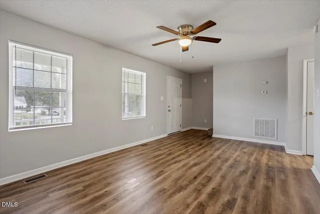 a view of empty room with wooden floor and fan