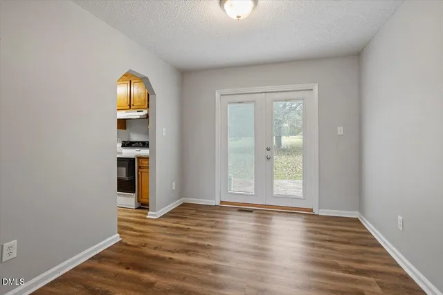 an empty room with wooden floor closet and windows