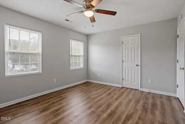 a view of an empty room with window and a chandelier fan