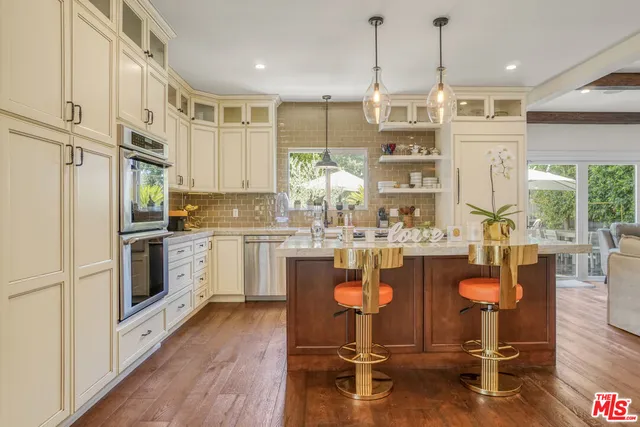 a kitchen with kitchen island granite countertop a stove a sink a dining table and chairs with wooden floor