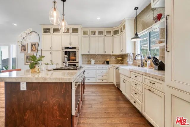 a kitchen with kitchen island granite countertop a sink a counter space appliances and cabinets