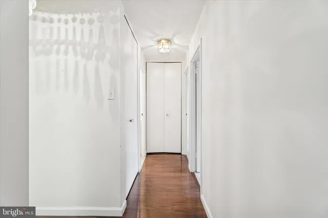 a view of a hallway with wooden floor and closet