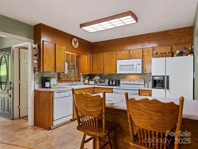a kitchen with stainless steel appliances granite countertop a stove top oven a refrigerator a kitchen island a dining table and chairs with wooden floor