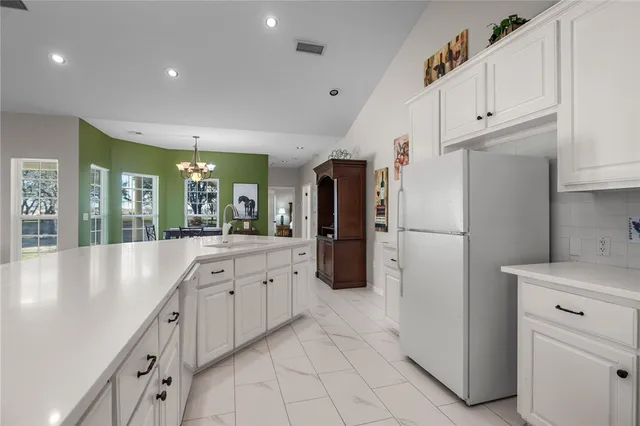 a bed sitting in a spacious bedroom next to a window and a chandelier