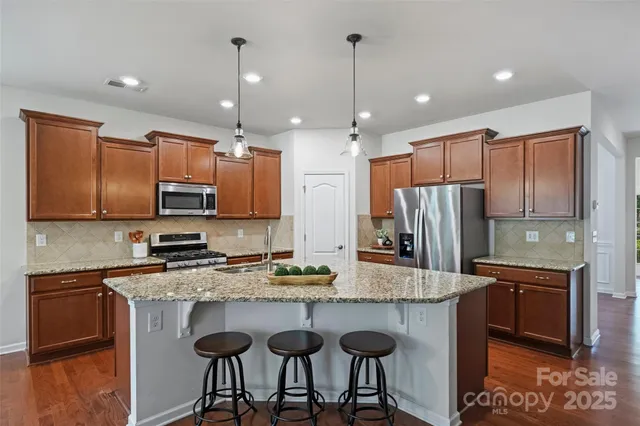 a kitchen with stainless steel appliances granite countertop a sink a stove a refrigerator and cabinets