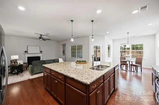 a kitchen with granite countertop kitchen island stainless steel appliances a dining table chairs stove and sink