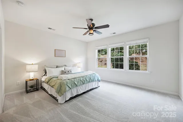 a bedroom with a bed ceiling fan and window