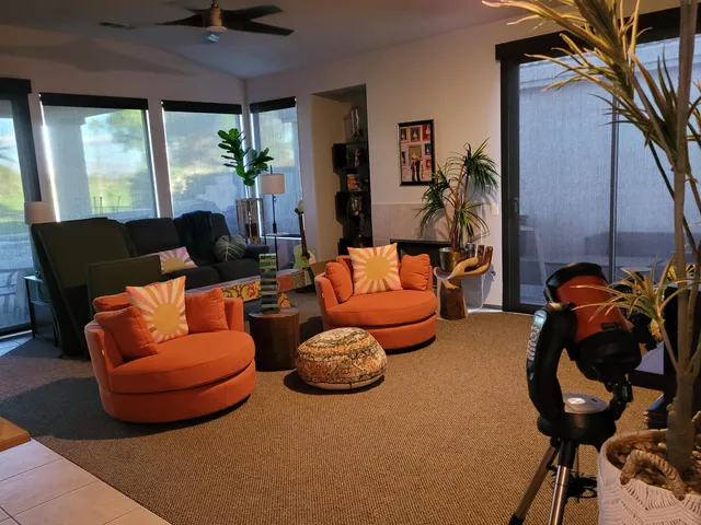 a living room with furniture a ceiling fan and a large window