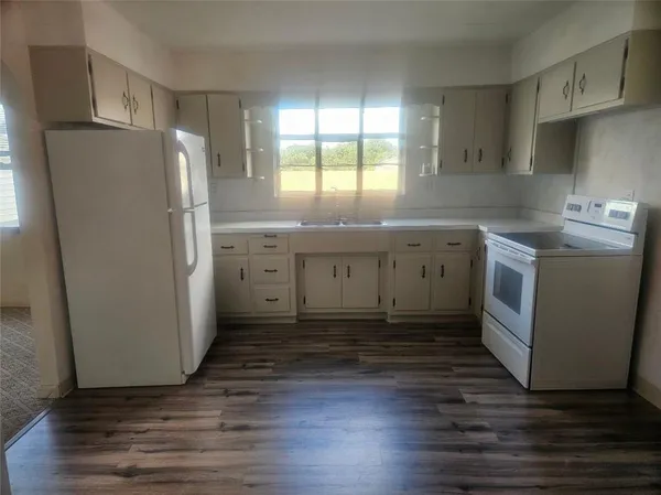 a kitchen with a refrigerator a sink and wooden floor