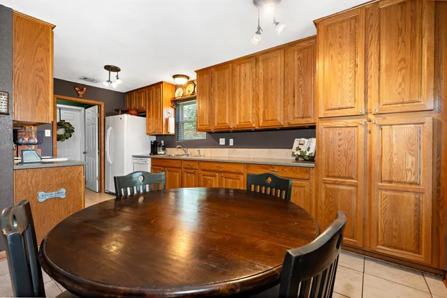 a kitchen with stainless steel appliances granite countertop a refrigerator a sink dishwasher and wooden cabinets with wooden floor