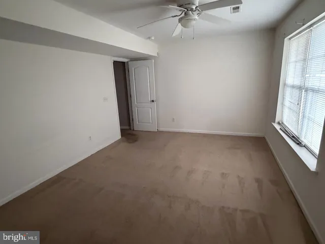 an empty room with a window and a ceiling fan
