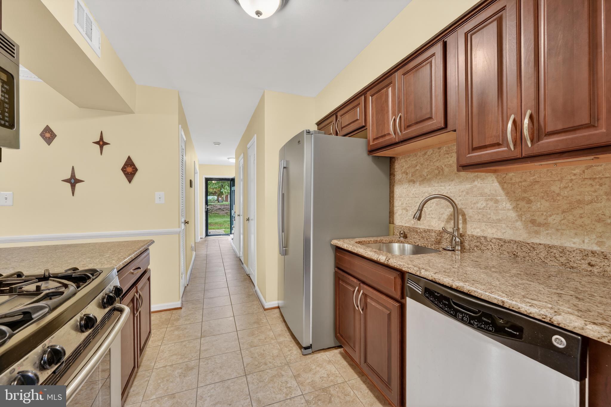 8139 Carrleigh Parkway Springfield, VA 22152 - Photo 9 of 27 a kitchen with stainless steel appliances granite countertop a stove a sink dishwasher and a refrigerator with wooden cabinets