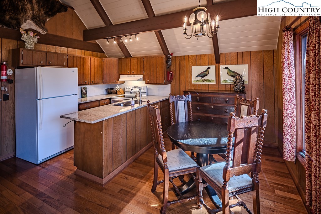 335 Cherry Drive Boone, NC 28607 - Photo 12 of 32 a kitchen with stainless steel appliances a stove a refrigerator and a dining table with wooden floors